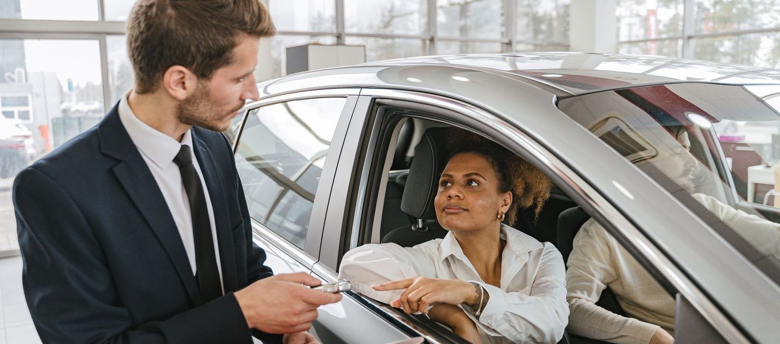 Vendedor entregando a chave do carro novo à cliente